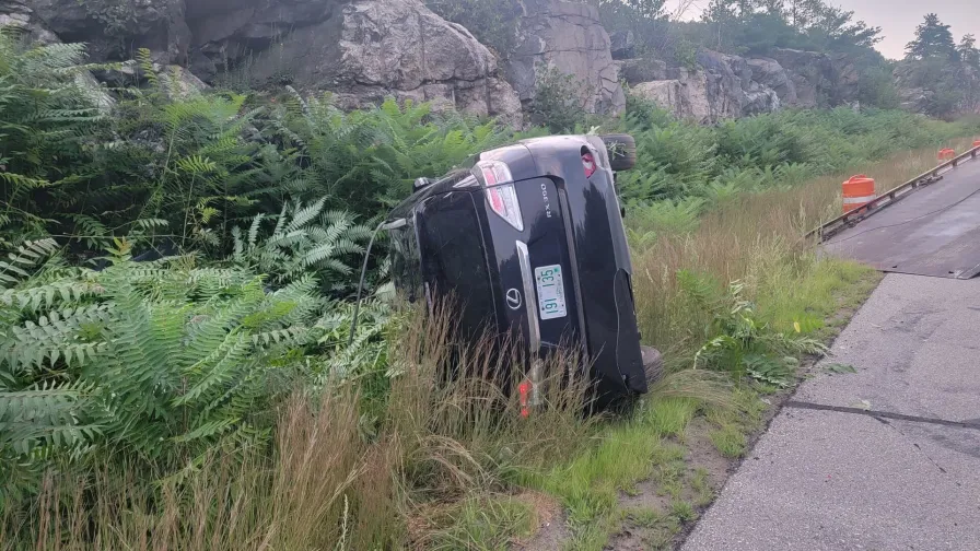 Black car toppled over beside the road in Manchester, NH